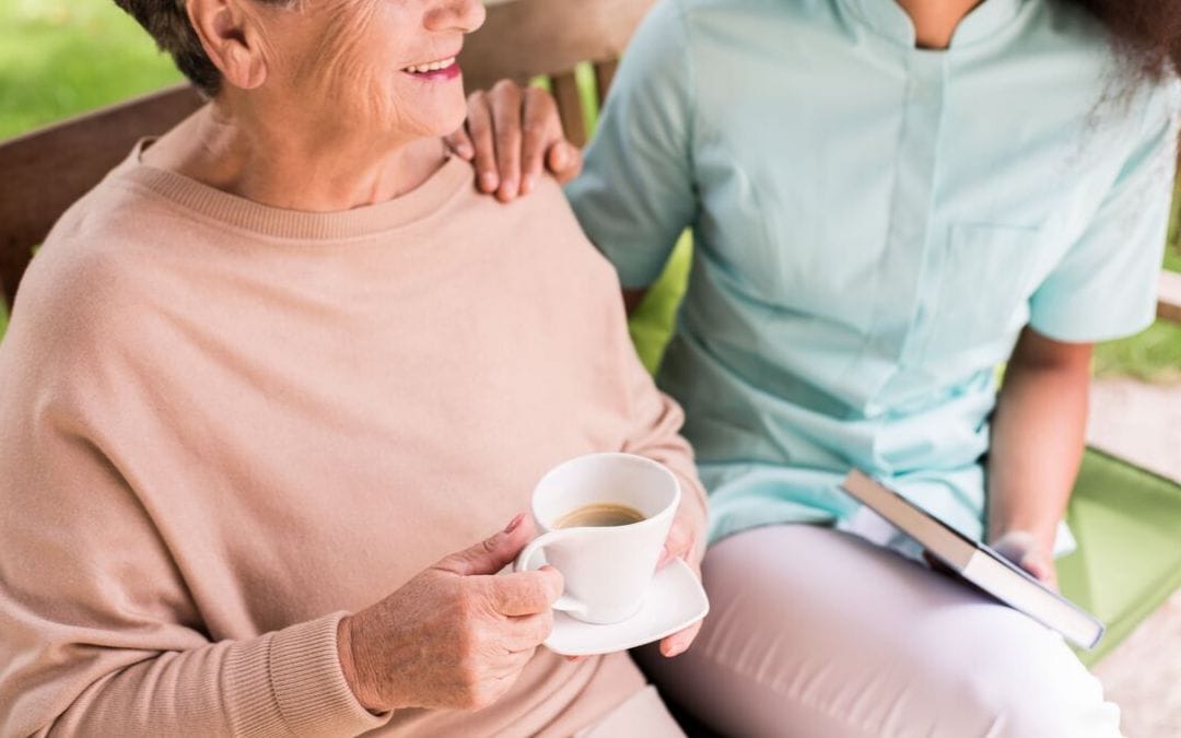 Senior woman sitting with woman having coffee outside