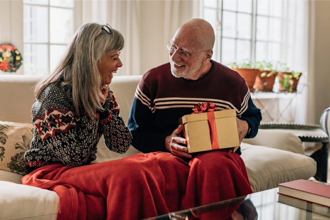 Senior couple exchanging gifts on sofa