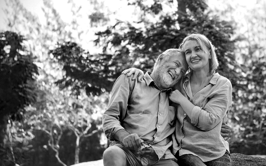 Elderly couple sitting outside embracing and smiling