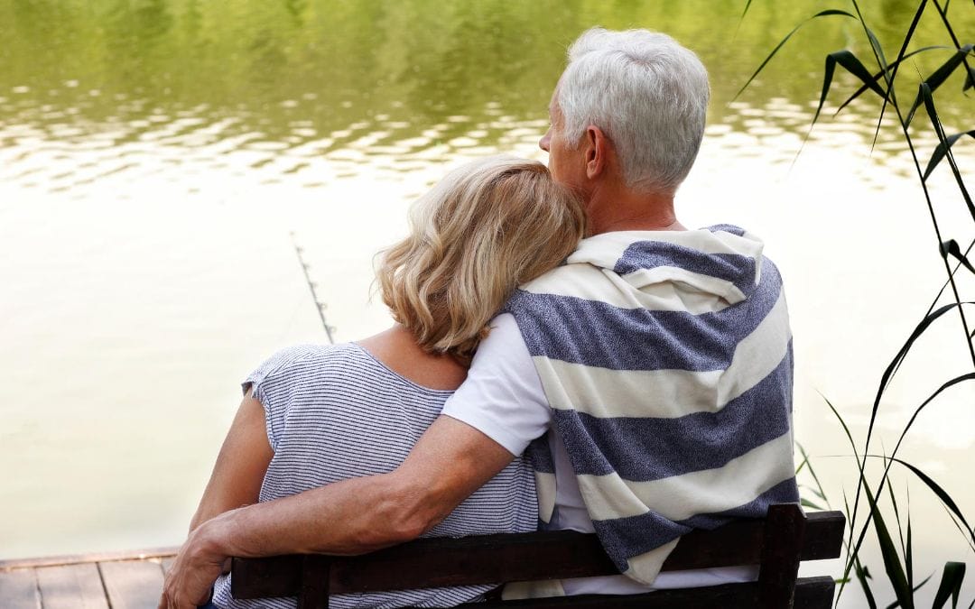 Senior couple sitting on bench in front of lake