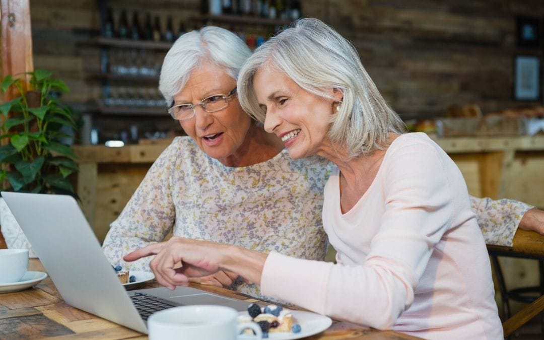 Elderly women using laptop together at coffee shop