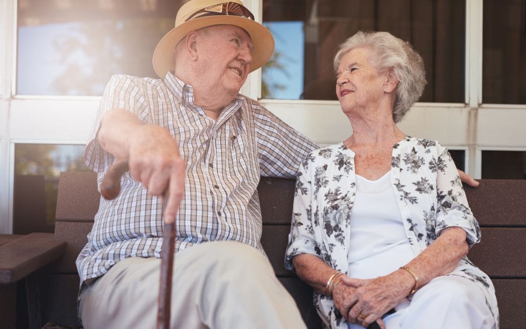 Elderly couple sitting on bench together outside