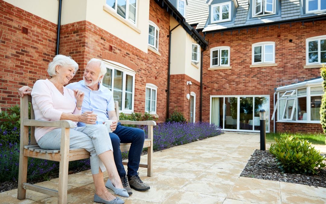Elderly couple sitting outside on bench together